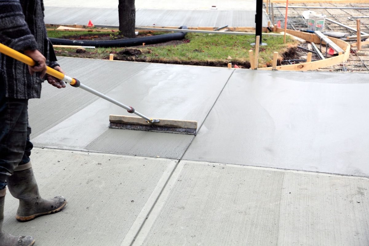 Crew member spreading fresh concrete with a rake