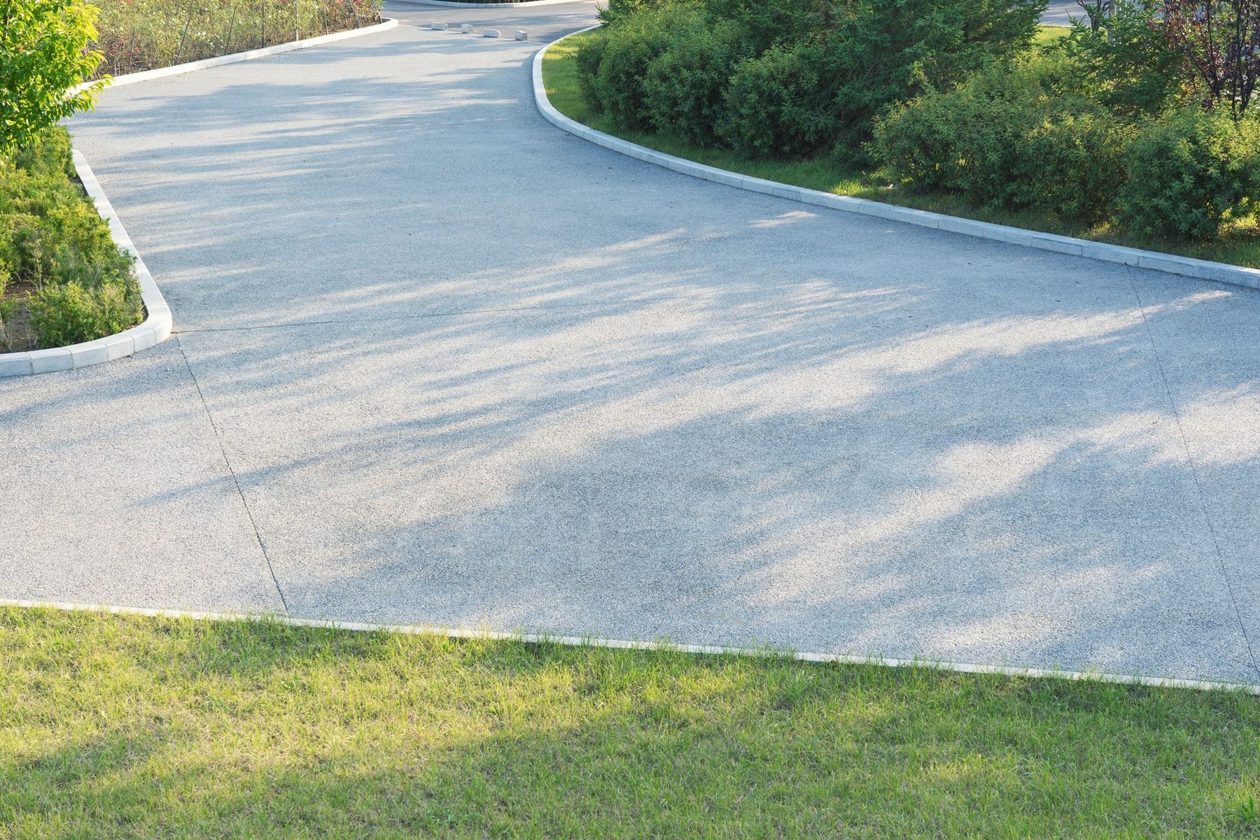 A freshly poured concrete driveway curving toward a home
