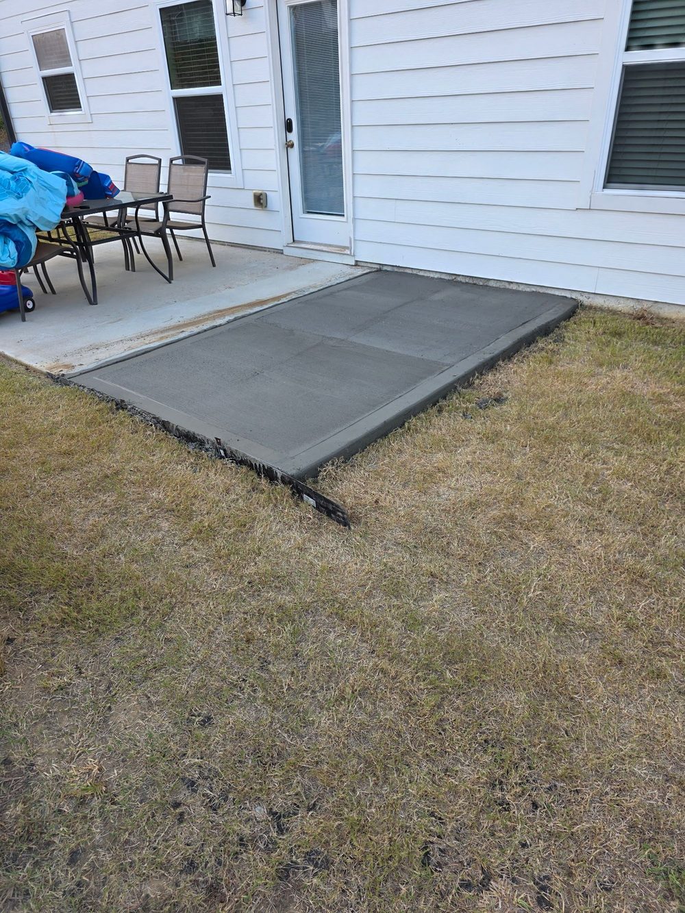 New broom-finished concrete patio behind a home