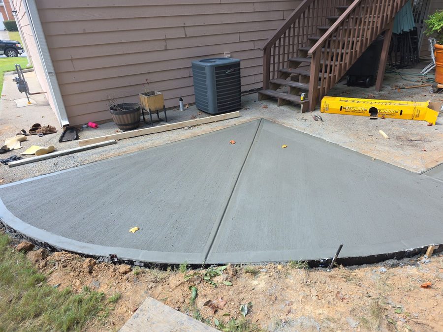 Fresh concrete pad beside a home with steps