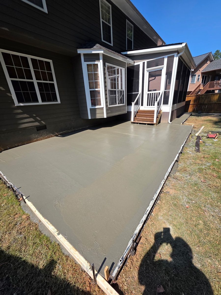 Wide new concrete slab beside a brick home